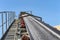 Close-up shot of the conveyor belt in the concrete plant with transport rollers, visible metal stairs and railings.