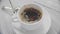 Close-up shot of a cup of coffee with milk. Pour sugar from the stick into a white cup of coffee and stir with a