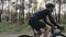 Close up shot of cyclist pedaling bike wearing black jersey, shorts, helmet and sunglasses. Back road carbon bicycle in the park.