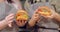Close-up shot of delicious freshly cooked burgers with fresh vegetables and cutlet in the hands of two young women in