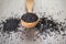 Close up shot of dried seeds of black cumin seeds kalinji on wooden spoon on rustic wooden background. Soft focus