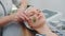 Close-up shot of facial massage with a jade roller on woman`s face at beauty salon