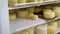 Close-up shot of a factory worker putting freshly cooked heads of cheese in the fridge.