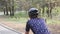 Close up shot of female cycling riding bike in a park wearing black helmet and blue jersey.