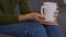 Close up shot of female hands holding cup of hot tea, warming palms, slow motion