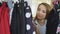 Close-up shot of female student shopping for clothes, looking through colourful garments on hangers, touching and moving