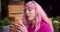 Close-up shot of a girl with pink hair tasting a delicious croissant in a street cafe. happy summer walk