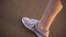 Close up shot of a girl`s legs in sneakers who walk along the beach.