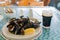 Close up shot of a glass of dark beer and a dish of mussels