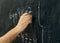 Close-up shot of a hand holding chalk and writing mathematical equations on the blackboard