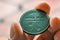 A close up shot of a hand holding a green token for the Hong Kong Star Ferry