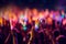 A close-up shot of hands holding glow sticks in the air at a rave party with a blurry crowd of people dancing in the background.