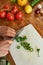 Close up shot of hands of man, chef cook slicing chili pepper with knife on chopping board