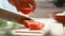 Close up shot hands of women using kitchen knife slide cut fresh tomato on wooden cutting board preparing for cooking