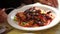 Close up shot of a hot salad, a person is going to eat it with a fork in a restaurant