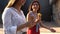 Close up shot of ice cream cones in hand of a woman walking with her friend. Two young women outdoors eating icecream on