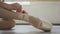 Close-up shot of little girl`s foot in pointe shoe and hands putting on professional footwear and tying ribbon around