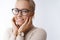 Close-up shot of lovely happy woman in glasses and watch enjoying soft silk skin touching cheeks and smiling delighted