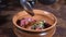 Close-up shot of male chef in black gloves preparing gourmet dish of meat tartare and mixing salad ingredientsin bowl