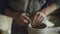 Close-up shot of male hands smoothing molded clay pot with wet sponge on spinning potter`s wheel in home studio