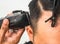 Close up shot of man getting trendy haircut. Male hairstylist serving client, making haircut using machine and comb. the concept