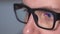 Close up shot of a man`s eyes with eyeglasses looking at a monitor