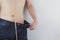 Close up shot of man with slim body measuring his waistline and torso. Healthy nutrition, diet and weight losing concept