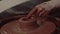 Close-up shot of a master female potter molding wet clay into a bowl on spinning potter`s wheel.