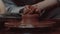 Close-up shot of a master female potter molding wet clay into a bowl on spinning potter`s wheel.