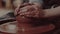 Close-up shot of a master female potter molding wet clay into a bowl on spinning potter`s wheel.