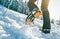 Close up shot of mountain boots with crampons and snow gaiters with backlight sun beams and snowy spruces on background . High