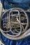 Close-up shot of an old silver French horn instrument, damaged instrument.