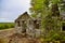 Close-up shot of old stone ruins of a forgotten lodge surrounded by trees on a cloudy day