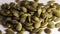 Close-up shot of a peeled pumpkin seed falling and spinning on a white table