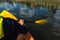 Close up shot of person canoeing in the river on a sunny day. Hands holding a paddle and rowing in flowing water