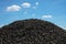 Close-up shot of a pile of coal against a blue cloudy sky at a quarry during daytime