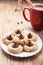 Close up shot of plate of peanut blossom chocolate cookies and hot chocolate on weathered brown wood