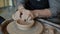 Close-up shot of potter`s hands smoothing molded pot on spinning throwing wheel in studio