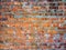 A close-up shot of a rough brick masonry wall lined with red clumsy brick for creativity, textures and background.