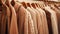 A close-up shot of a row of light brown coats and sweaters on hangers in a store, highlighting the timeless and