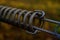 Close up shot of a rusty metal spring partially attached to a wooden fence, with peeling paint