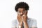 Close-up shot of scared and insecure young african american man with afro hairstyle in watch and glasses biting