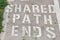 Close-up shot of "shared path ends" road marking on a path