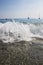 Close up shot of small breaking waves on the beach side. Lovely small surge with sand and boats, blue ocean water and boats in the