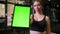 Close-up shot of sportswoman with ponytail shows tablet with chromakey green screen being positive in gym,