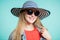 Close up shot of stylish woman in sunglasses smiling against blue background. Beautiful female model striped hat