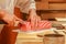 A close-up shot of a sushi chef cutting a chunk of fatty tuna on a cutting board