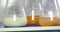 Close up shot of three Erlenmeyer flasks and some food examples in it being mixed by a mixing device