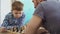 Close-up shot of two people father and son playing chess, thinking about next move and moving chessmen on board