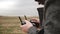 Close-up shot of unrecognizable man looking at black aerial drone remote controller device display on a cloudy day.